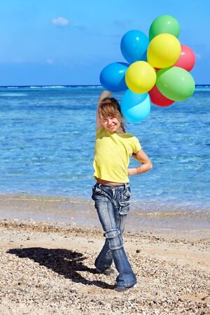 little girl playing with balloons at the beach.の写真素材