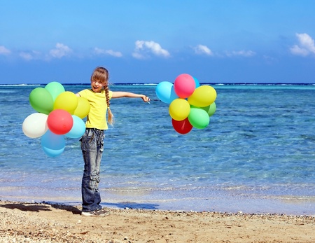 little girl playing with balloons at the beach.の写真素材