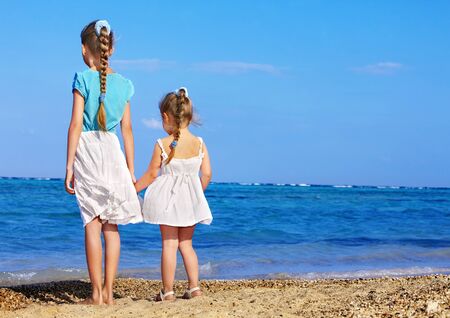 Children holding hands walking on the beach. Rear view.の写真素材