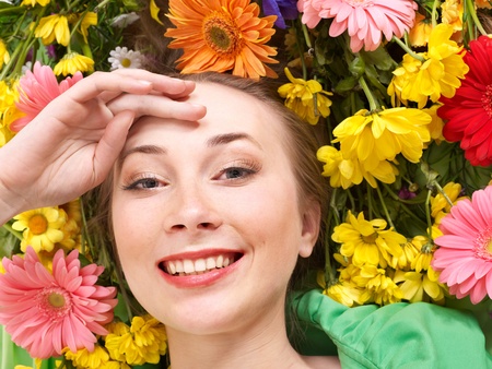 Beautiful young woman in flowers touching face.の写真素材