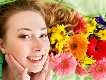 Beautiful young woman in flowers touching face.の写真素材