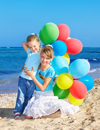 little girl playing with balloons at the beach.の写真素材
