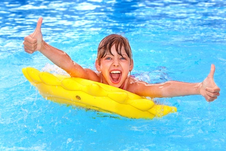 Children sitting on inflatable ring in swimming pool.の写真素材