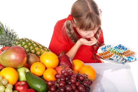 Child with fruit and vitamin pill. Isolated.の写真素材