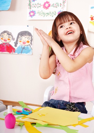 Little girl glue paper in preschool. Child care.の写真素材