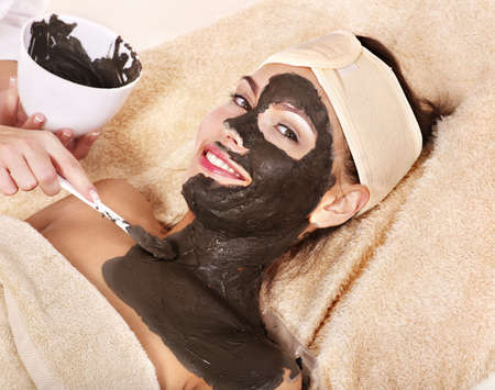 Beautiful girl having clay body mask apply by beautician.の写真素材