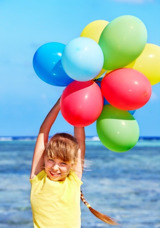 little girl playing with balloons at the beach.の写真素材