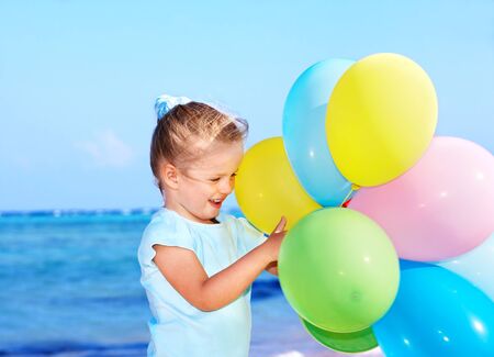 little girl playing with balloons at the beach.の写真素材