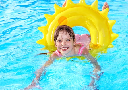 Children sitting on inflatable ring in swimming pool.の写真素材