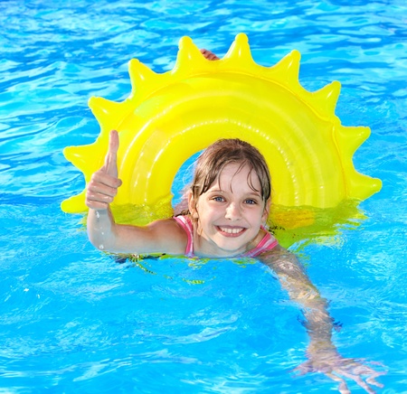 Children sitting on inflatable ring in swimming pool.の写真素材