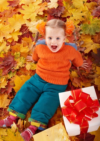 Little girl in autumn orange hat on leaves and gift box. Outdoor.の写真素材