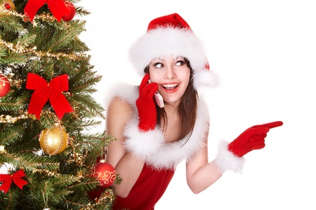 Girl in santa hat call mobile phone by christmas tree. Isolated.の写真素材