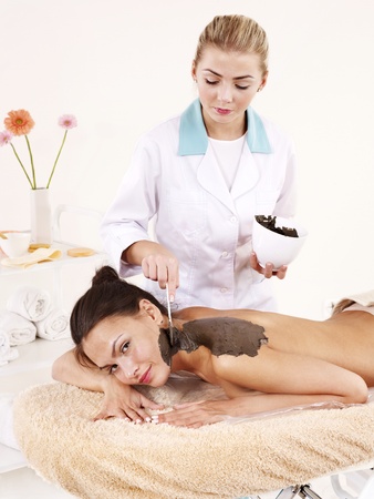 Beautiful girl having clay body mask apply by beautician.の写真素材