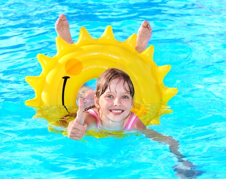 Children sitting on inflatable ring in swimming pool.の写真素材