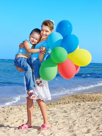 little girl playing with balloons at the beach.の写真素材