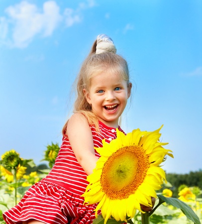 Child holding sunflower outdoor.の写真素材