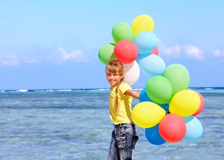 little girl playing with balloons at the beach.の写真素材