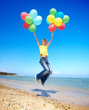 little girl playing with balloons at the beach.の写真素材