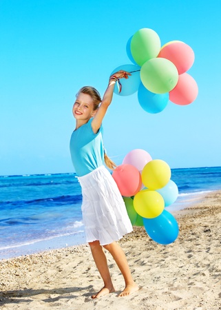 little girl playing with balloons at the beach.の写真素材