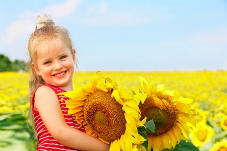 Child holding sunflower outdoor.の写真素材
