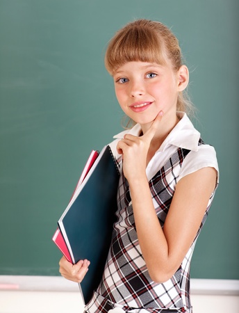 Happy schoolchild in classroom near blackboard.の写真素材