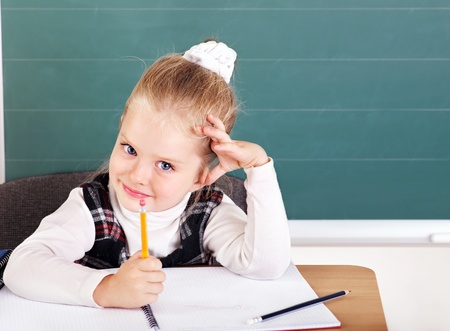 Happy schoolchild in classroom near blackboard.の写真素材