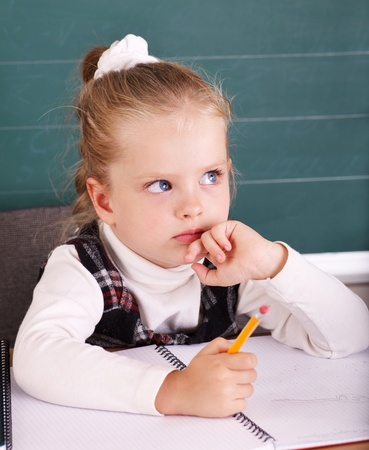 Happy schoolchild in classroom near blackboard.の写真素材