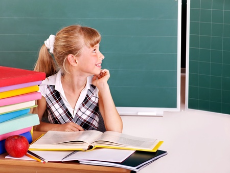 Happy schoolchild in classroom near blackboard.の写真素材