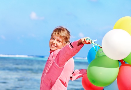little girl playing with balloons at the beach.の写真素材