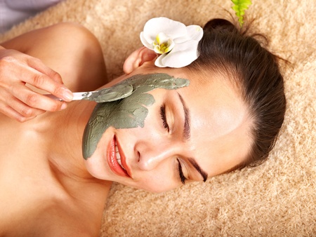 Beautiful girl having clay body mask apply by beautician.の写真素材