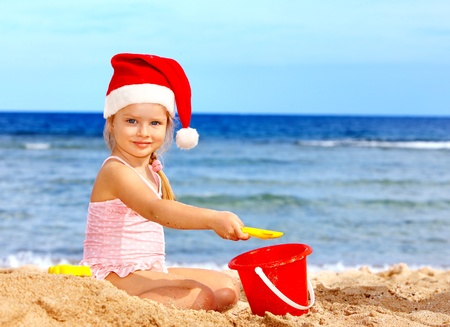 Child in santa hat playing on  beach. Summer New Year.の写真素材
