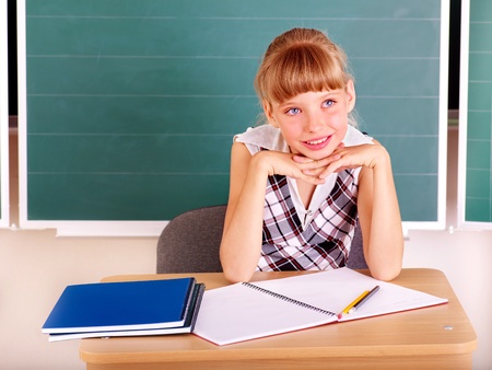 Happy schoolchild in classroom near blackboard.の写真素材