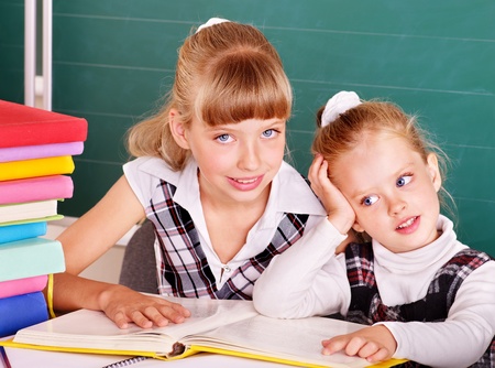 Happy schoolchildren in classroom near blackboard.の写真素材