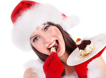 Christmas girl in red santa hat eating cake on plate. Isolated.の写真素材