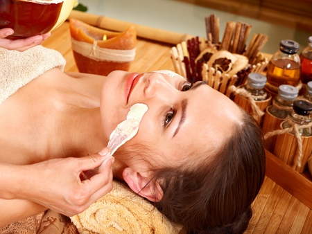 Beautiful girl having clay facial mask apply by beautician.の写真素材