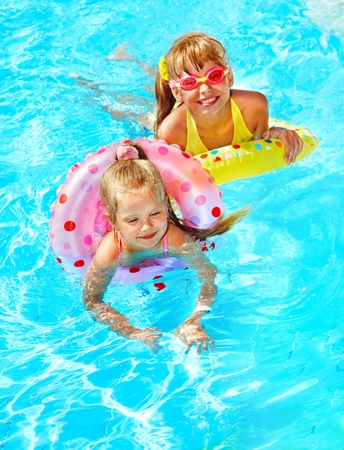 Children sitting on inflatable ring in swimming pool.の写真素材