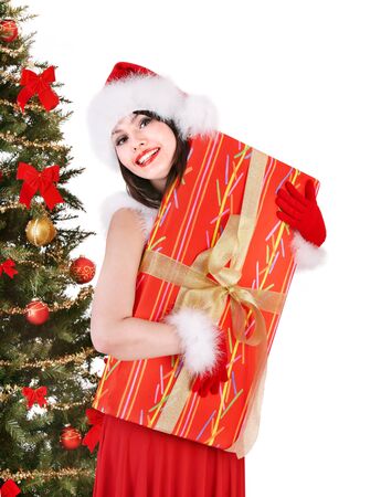 Girl in santa hat holding stack  gift box by christmas tree.. Isolated.の写真素材