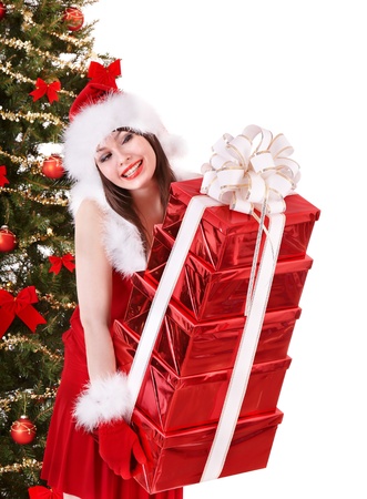 Girl in santa hat giving stack red gift box by christmas tree. Isolated. の写真素材