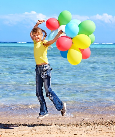 little girl playing with balloons at the beach.の写真素材