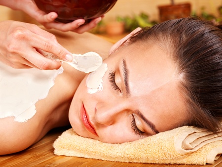 Beautiful girl having clay body mask apply by beautician.の写真素材
