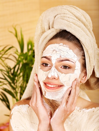 Beautiful girl having clay facial and body mask apply by beautician.の写真素材