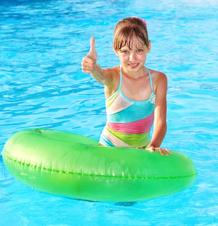 Children sitting on inflatable ring in swimming pool.の写真素材