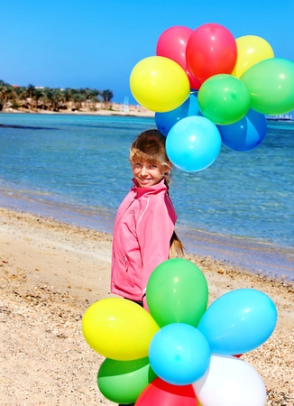 little girl playing with balloons at the beach.の写真素材
