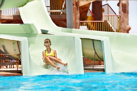 Child on water slide at aquapark. Summer holiday.