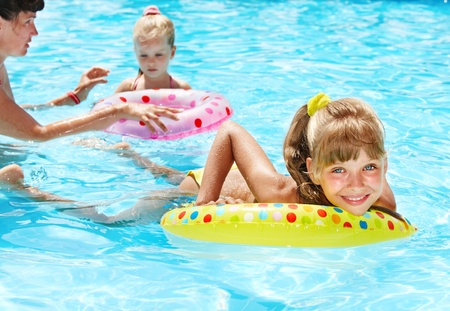 Happy family with children sitting on inflatable ring in swimming pool.の写真素材