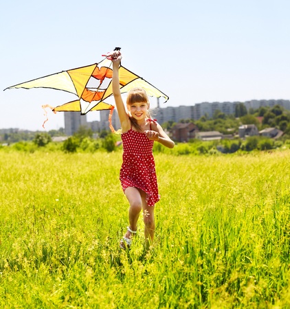 Child flying kite outdoor. little girl running across  green grass.の写真素材