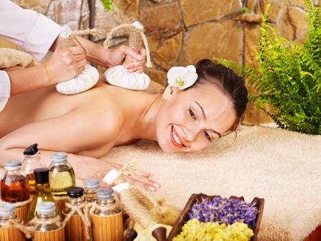 Woman getting thai herbal compress massage in spa.の写真素材