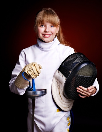 Child in fencing costume holding epee . Black background.の写真素材