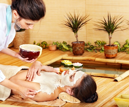 Beautiful girl having clay facial mask apply by beautician.の写真素材