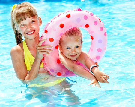 Children sitting on inflatable ring in swimming pool.の写真素材